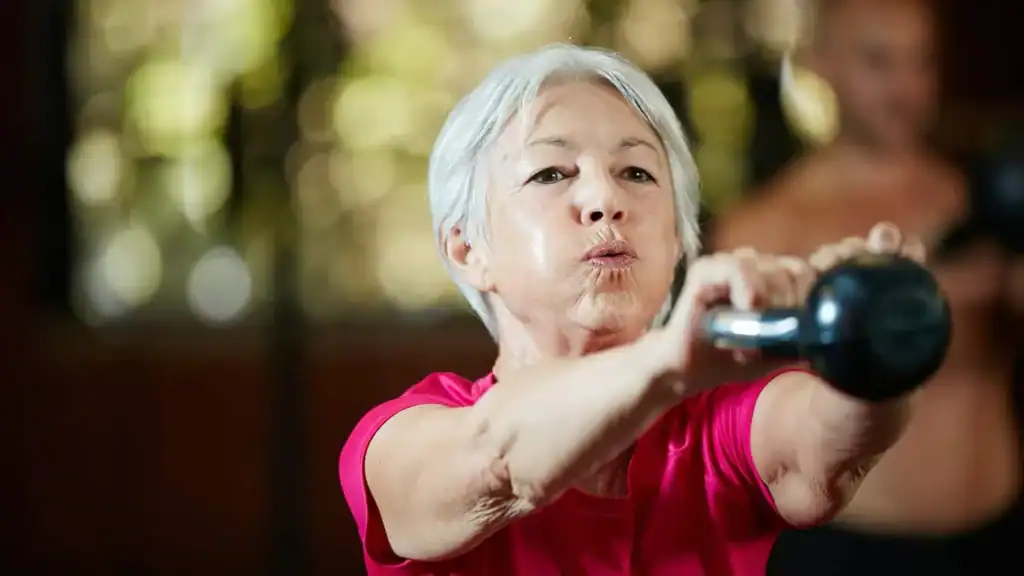 Older woman doing weight training Wisley to help her strength and longevity 