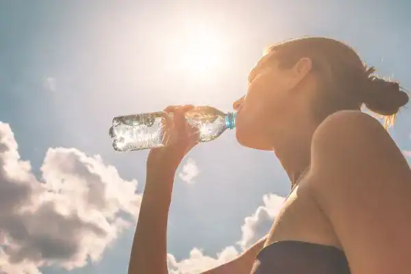 Image of woman drinking water to hydrate Wisley after run.